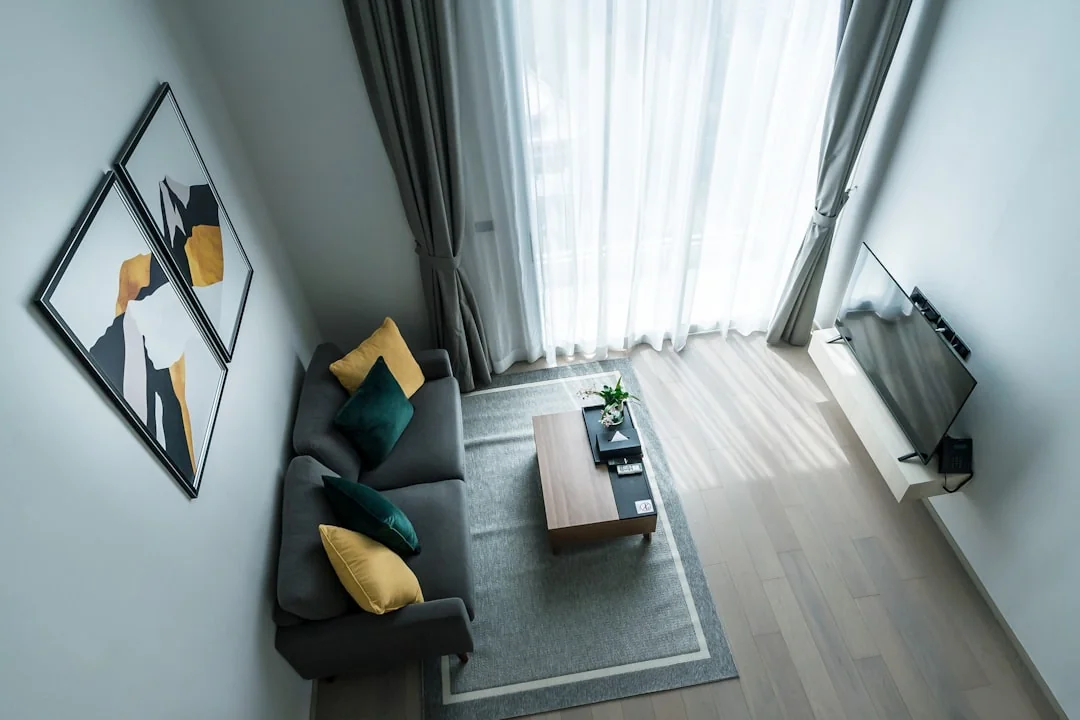 A professional cleaner in protective gear vacuuming the floor in a modern living room.